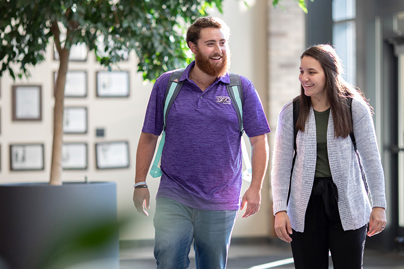 Two students walking in Academic Complex Building