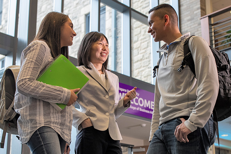 Professor talking with two students in the Glynn Atrium