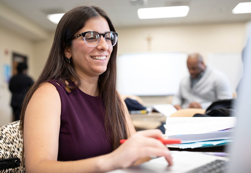 Student with glasses scrolling on a laptop